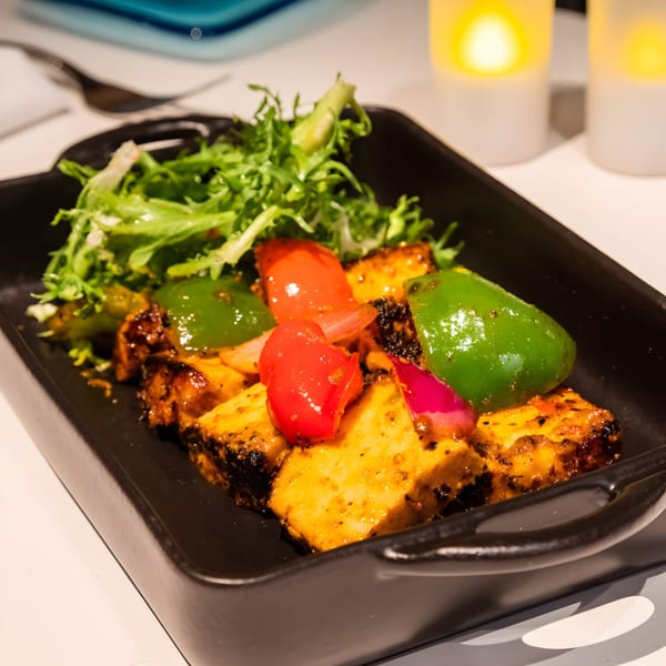 Indian paneer tikka with red and green bell peppers, onions, and a side salad.